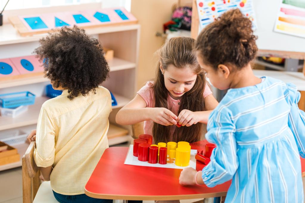 Τα παιδιά παίζουν πολύχρωμο εκπαιδευτικό παιχνίδι στο γραφείο στο Montessori σχολείο - Φωτογραφία, εικόνα