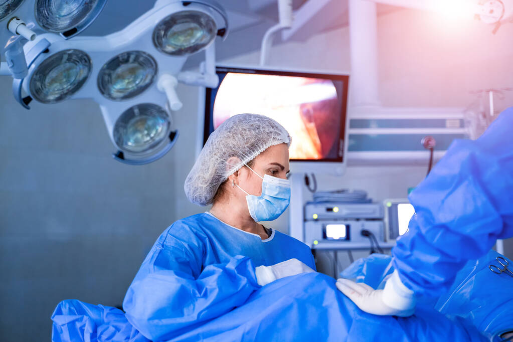 Equipo médico realizando operación quirúrgica en quirófano moderno - Foto, imagen