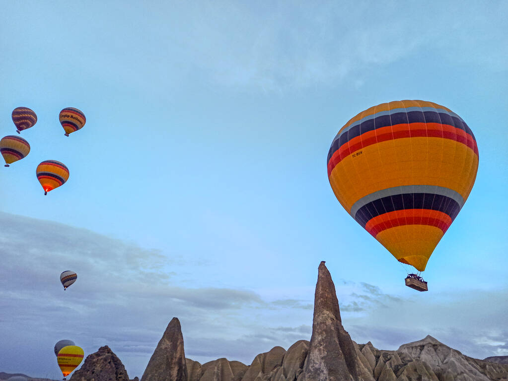 Kleurrijke Hot Air ballonnen vliegen over Cappadocië in de vroege ochtend in de winter met donkere ochtend in Turkije - Foto, afbeelding