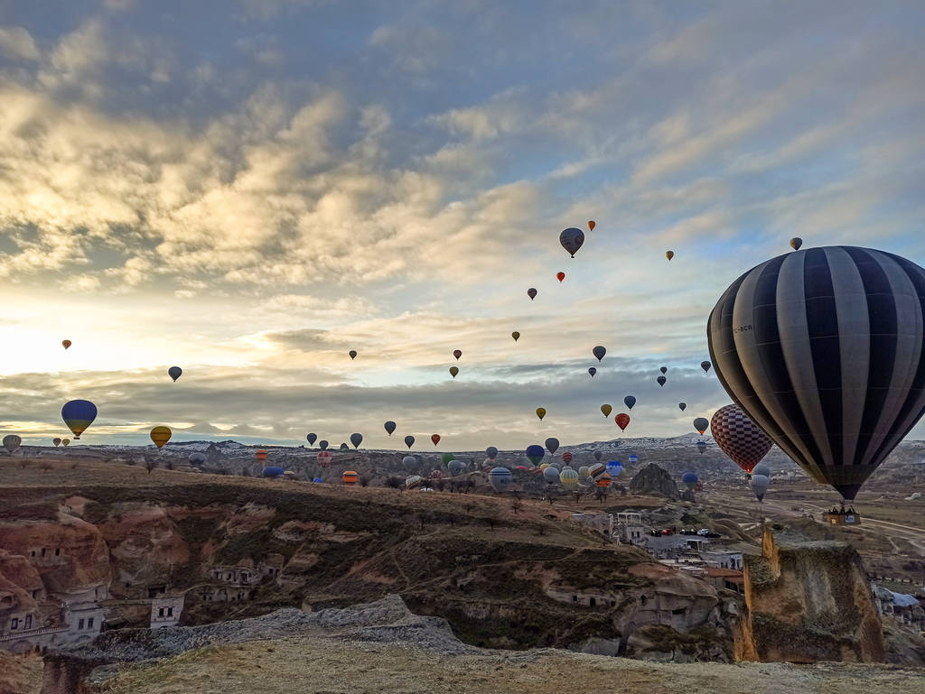 Kleurrijke heteluchtballonnen vliegen bij zonsopgang met rotsachtig landschap in Cappadocië, Turkije - Foto, afbeelding