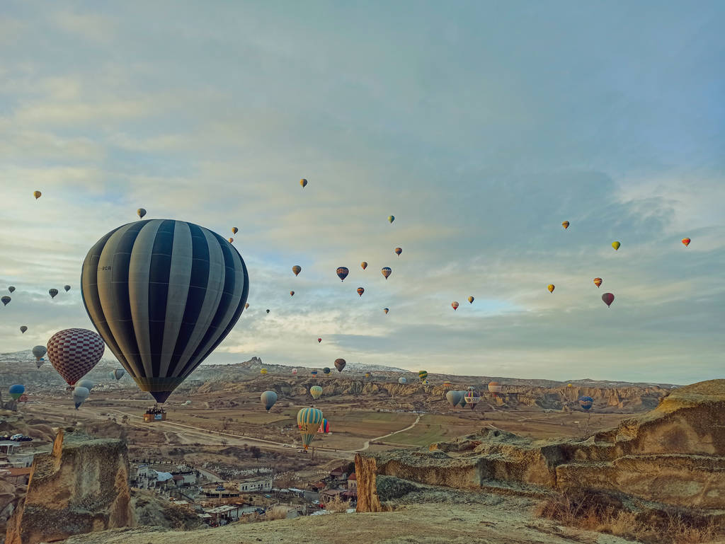 Balões de ar quente coloridos voando ao nascer do sol com paisagem rochosa na Capadócia, Turquia
 - Foto, Imagem