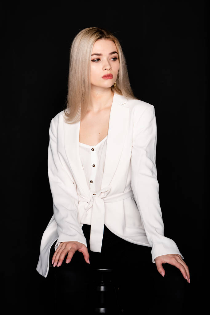 κοντινό πορτραίτο όμορφου νεαρού μοντέλου με ξανθά μαλλιά και μαύρα ρούχα, ποζάρει σε φωτογραφικό στούντιο σε σκούρο φόντο - Φωτογραφία, εικόνα