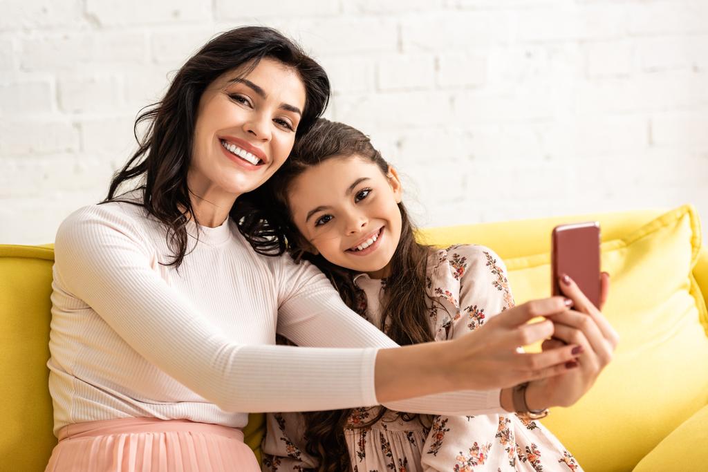 happy mother and daughter smiling at camera while taking selfie on mothers day - Photo, Image
