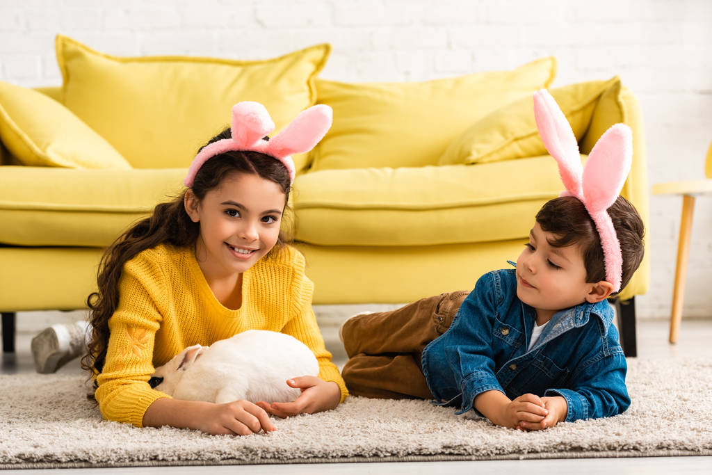adorable kids in bunny ears lying on floor near white funny rabbit - Photo, Image