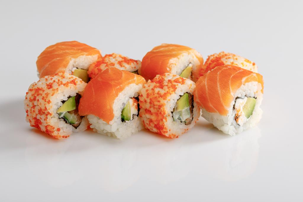 köstliches Philadelphia und Kalifornien-Sushi mit Lachs und Masago-Kaviar auf weißem Hintergrund - Foto, Bild