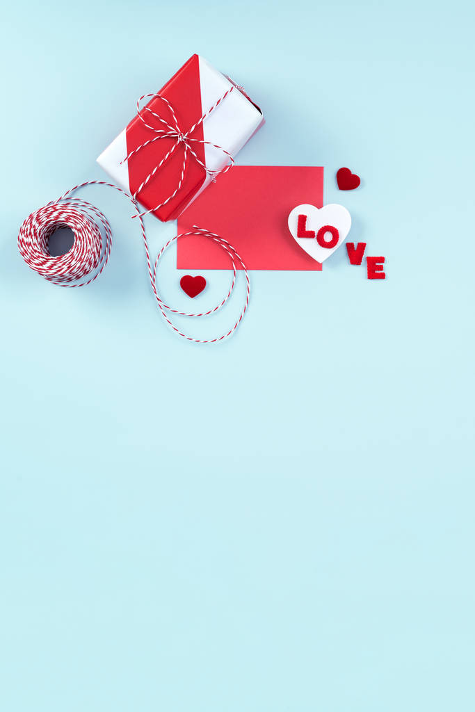 Día de San Valentín, concepto de diseño de arte del día de la madre para la promoción - Caja de regalo envuelta roja y blanca aislada sobre fondo de color azul claro pastel, posición plana, vista superior
. - Foto, imagen