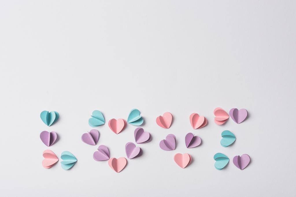 κορυφή άποψη της αγάπης γράμματα κατασκευασμένα από πολύχρωμες καρδιές χαρτί σε λευκό φόντο - Φωτογραφία, εικόνα