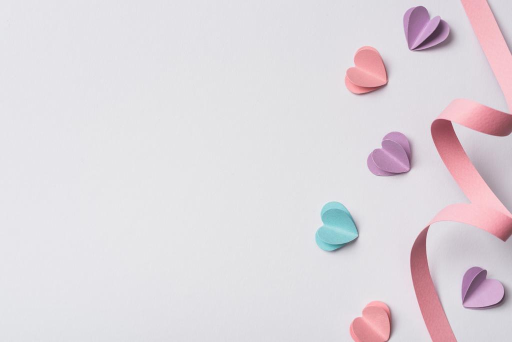 верхний вид на маленькие бумажные сердечки и розовые бумажные завихрения на белом фоне
 - Фото, изображение