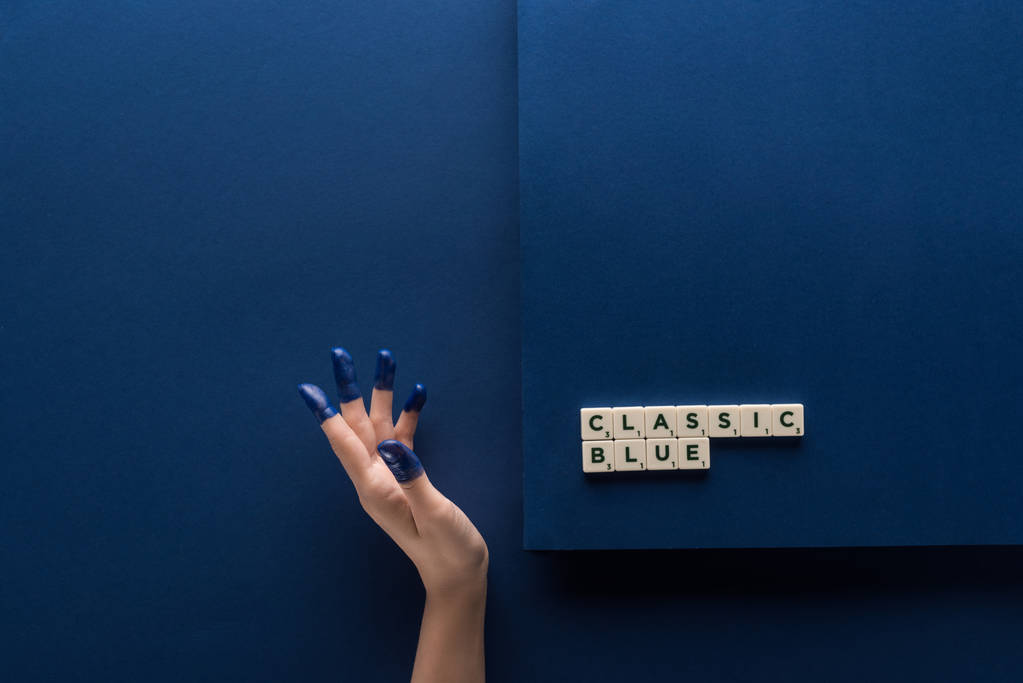 vista recortada de la mujer con los dedos pintados cerca de letras azules clásicas en cubos sobre fondo azul
 - Foto, Imagen