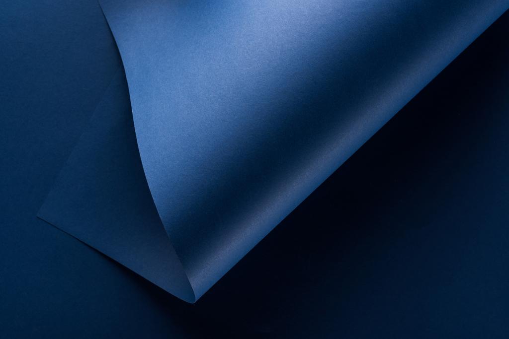 bovenaanzicht van gebogen blauwe papieren achtergrond - Foto, afbeelding