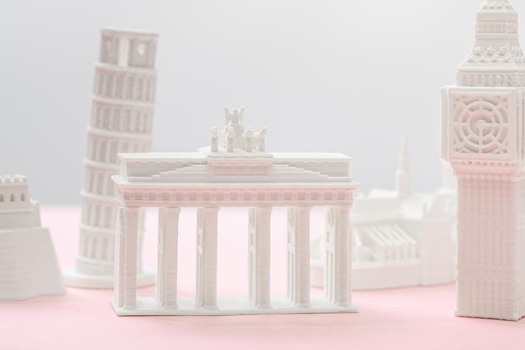グレーとピンクのビッグ・ベン・タワー像の近くのブランデンブルク門フィギュアの選択的焦点  - 写真・画像