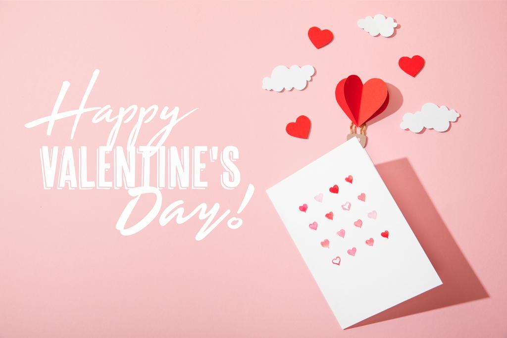 vista superior do cartão de saudação com corações perto de papel coração em forma de balão de ar em nuvens e feliz dia dos namorados lettering em rosa
 - Foto, Imagem