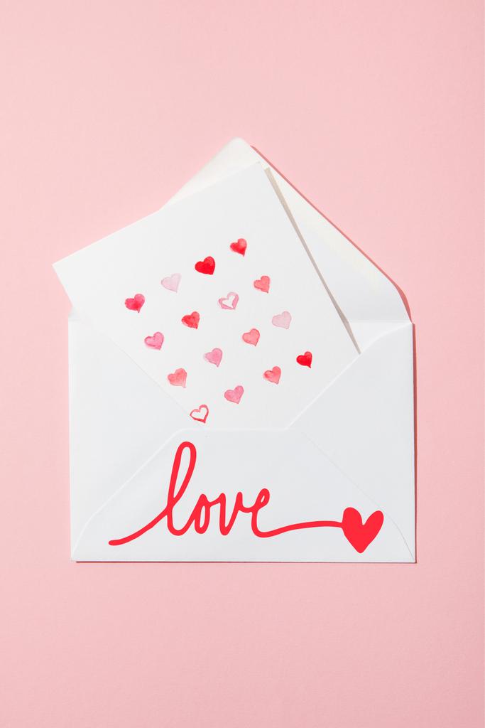 top view of greeting card with hearts in white envelope with love lettering on pink - Photo, Image