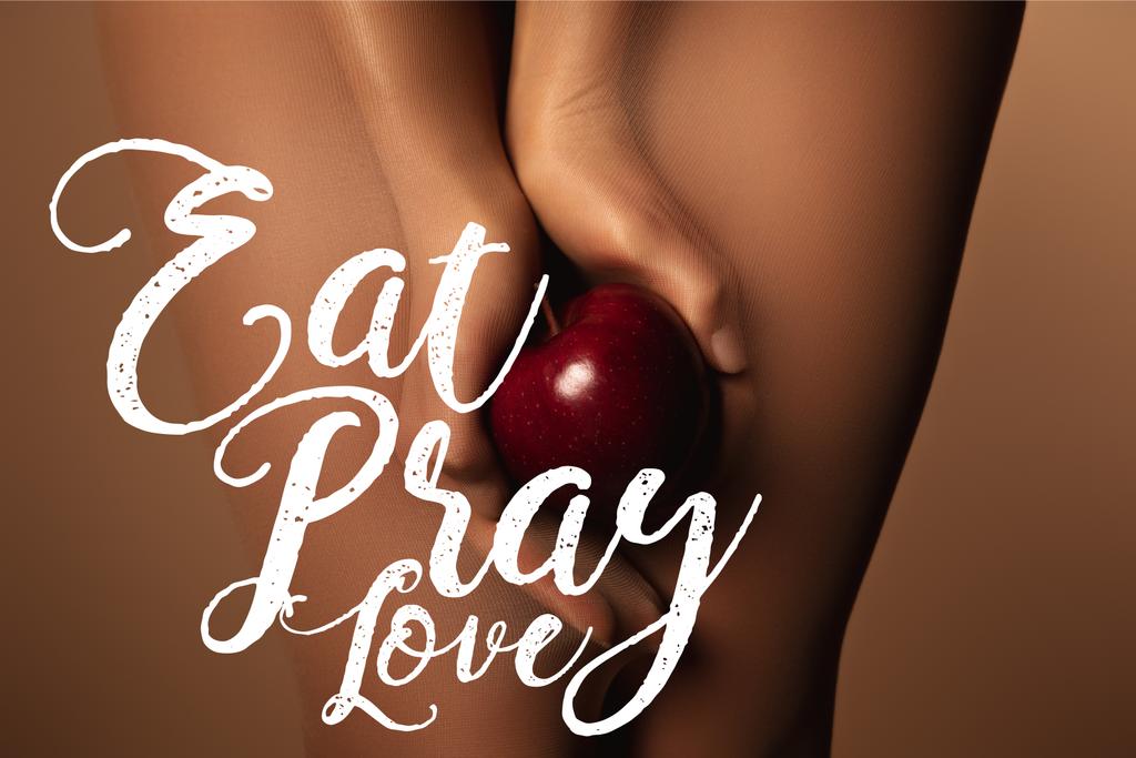 обрезанный вид женщины в нейлоновых колготках держа спелое красное яблоко рядом с едой молиться любовь буквы на коричневый
 - Фото, изображение