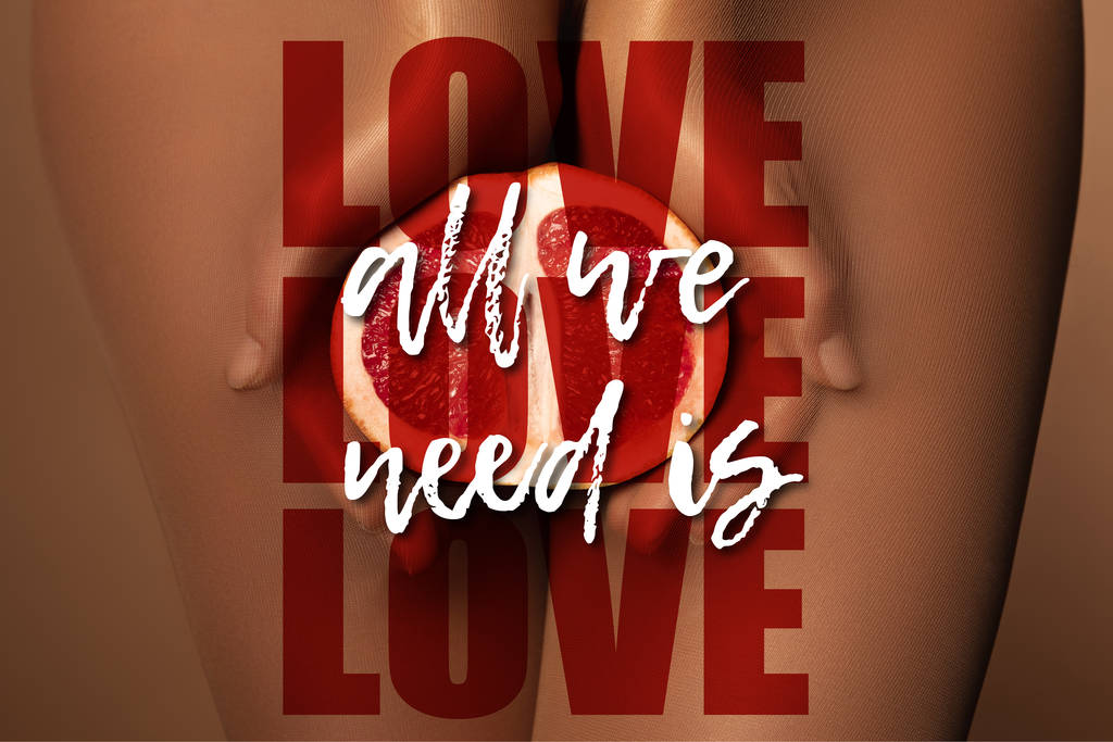 cropped view of woman in nylon tights holding grapefruit half near all we need is love lettering on brown - Photo, Image