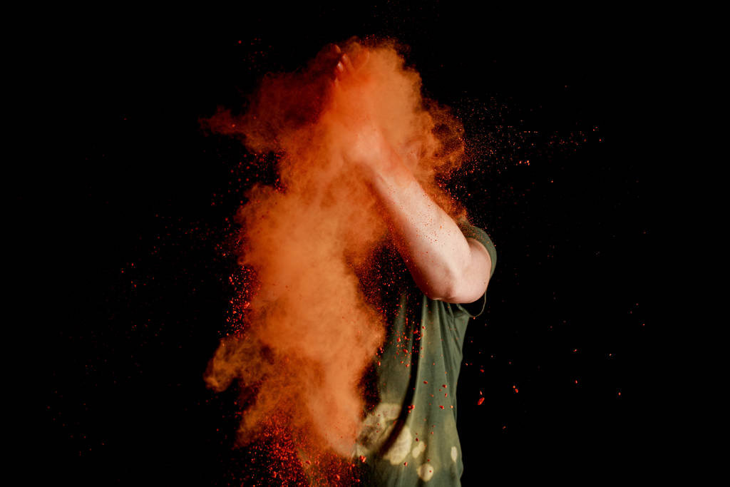 nő narancs színű holi festék robbanás előtt arc fekete háttér - Fotó, kép