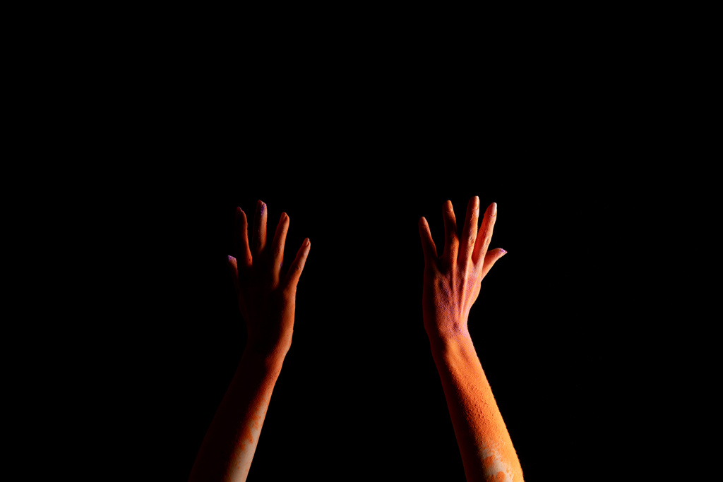 vista recortada de las manos femeninas con polvo de pintura holi de color naranja aislado en negro
 - Foto, Imagen
