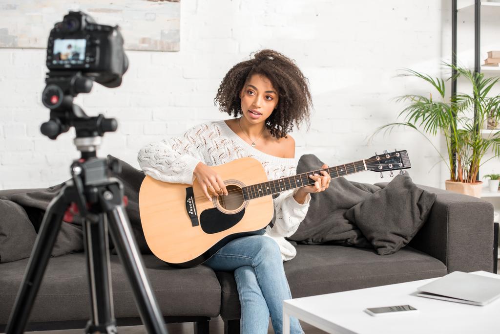 foyer sélectif de belle influenceuse afro-américaine jouant de la guitare acoustique près de l'appareil photo numérique
  - Photo, image