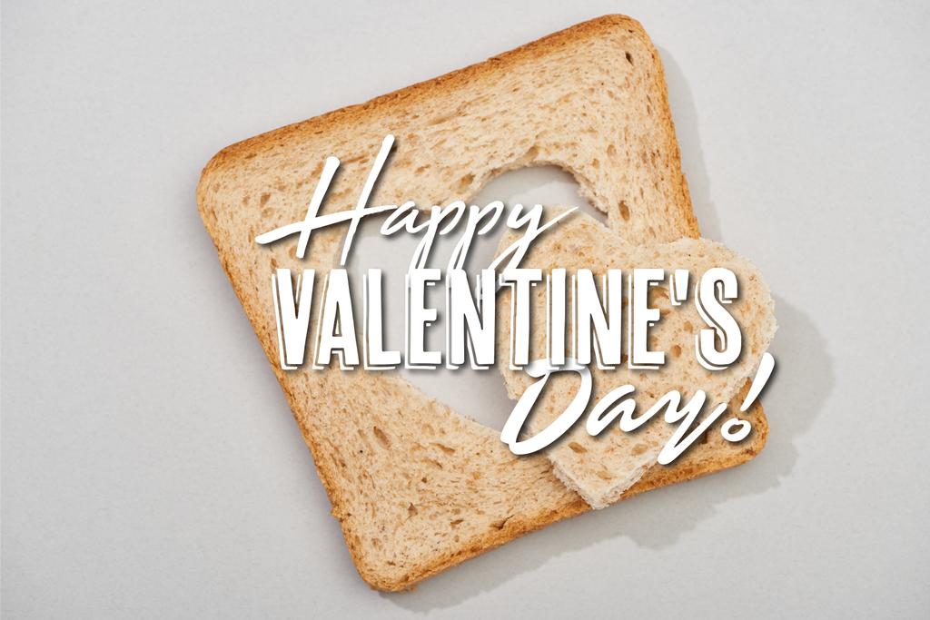 Vue du dessus de tranche de pain avec coeur sculpté et joyeux lettrage Saint-Valentin sur fond gris
 - Photo, image