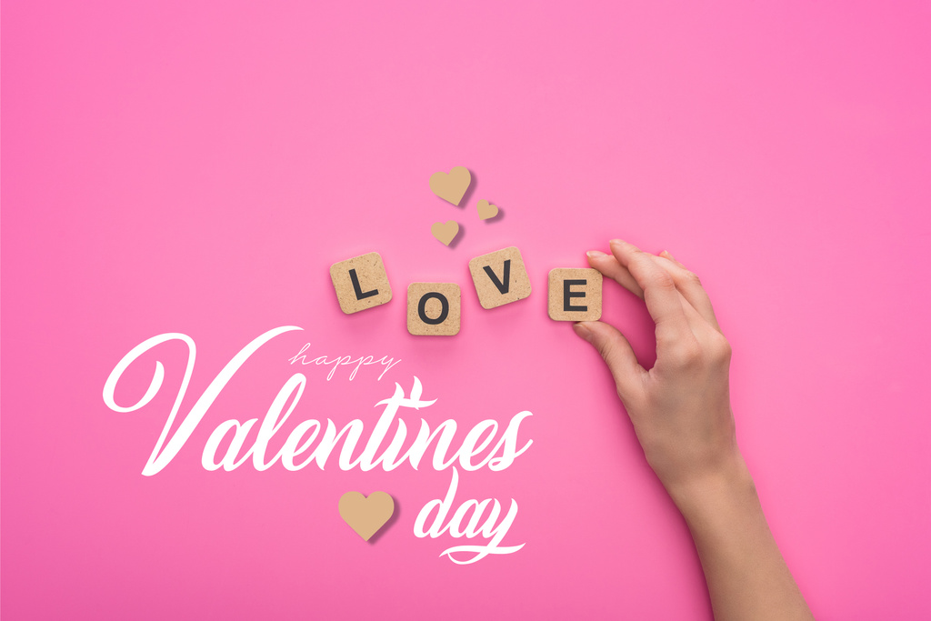 visão parcial da mulher segurando cubos com letras de amor no fundo rosa com feliz dia dos namorados lettering
 - Foto, Imagem