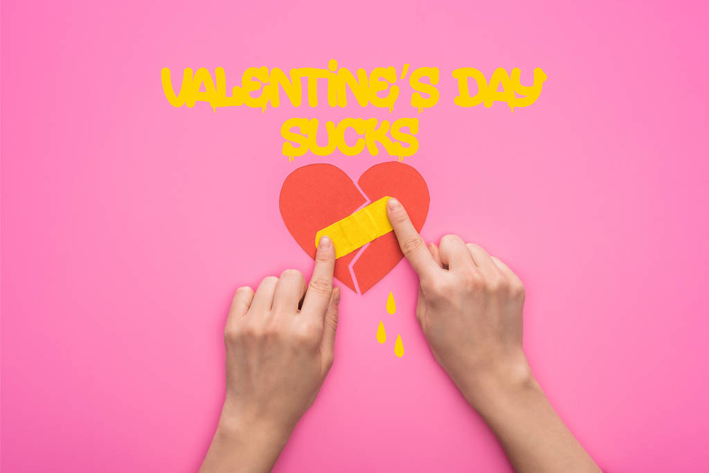 cropped view of woman putting patch on broken paper heart isolated on pink with valentines day sucks lettering - Photo, Image