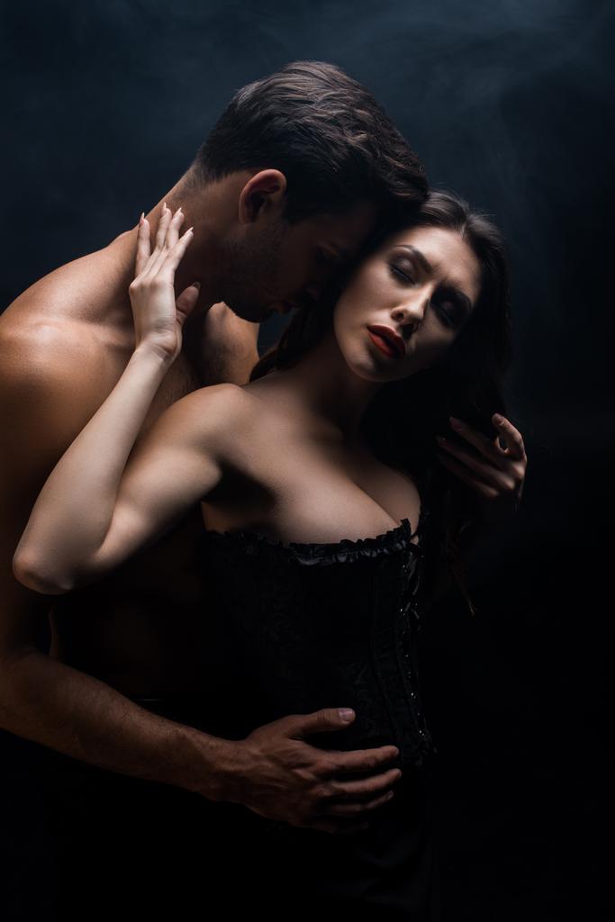 Musculoso hombre tocando sexy novia en corsé aislado en negro
 - Foto, imagen