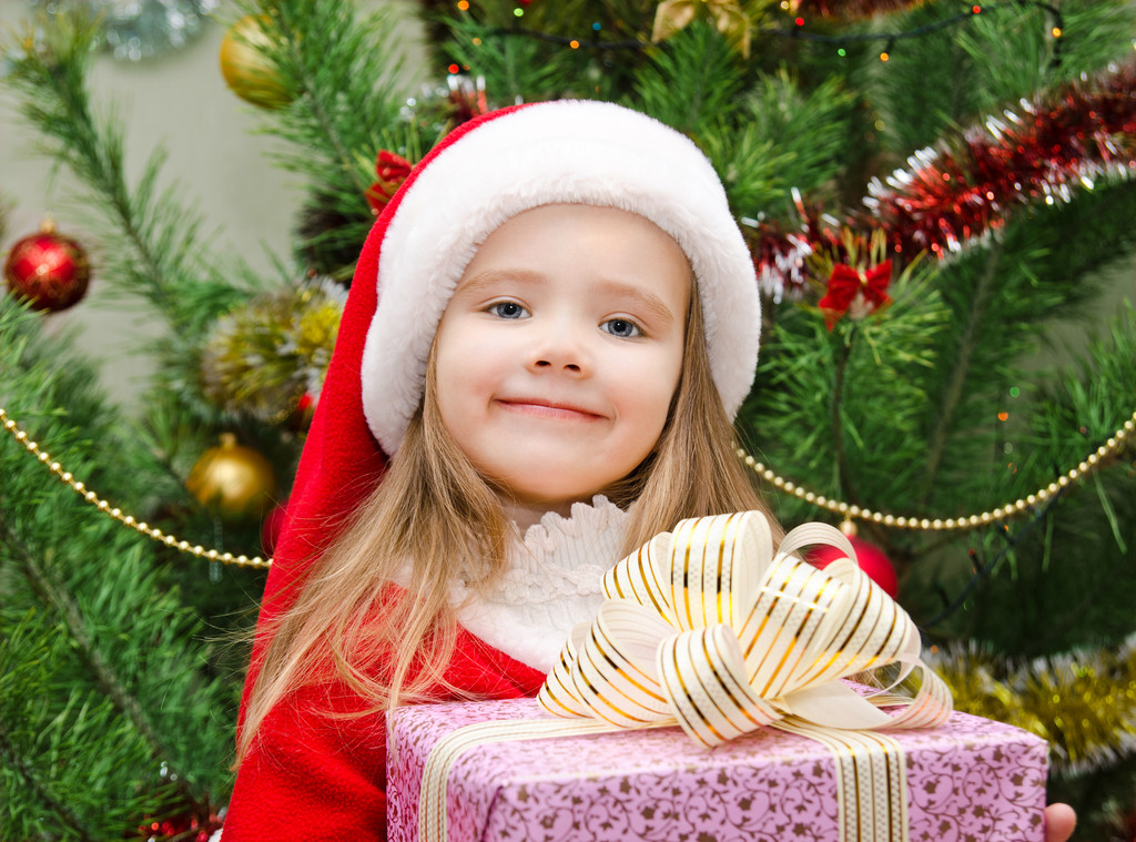 klein meisje in kerstmuts met heden hebben een kerst - Foto, afbeelding