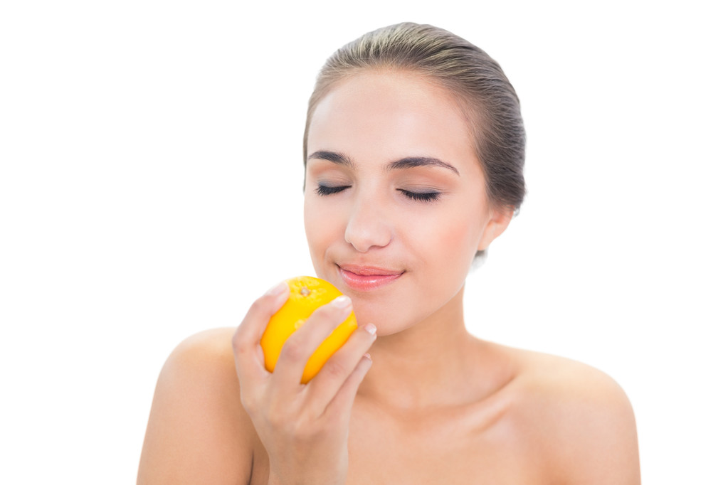 Femme souriante sentant sur une orange
 - Photo, image