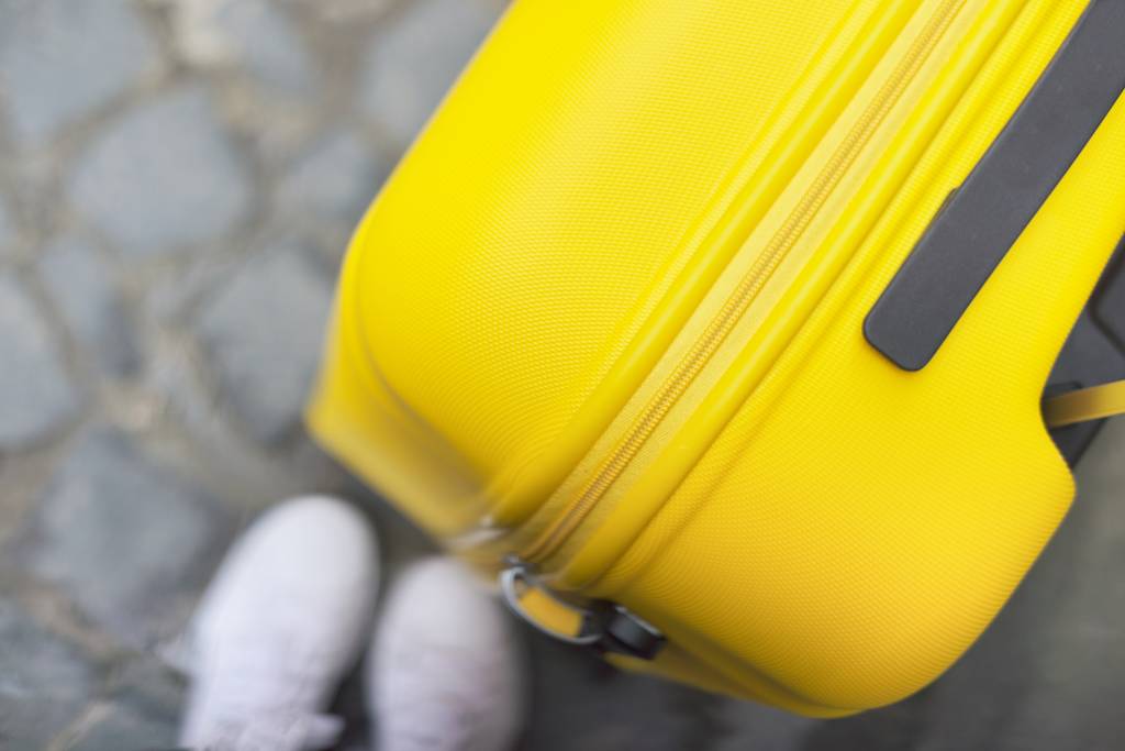 Концепция туристического туризма, крупным пластмассовым чемоданом из желтого пластика
 - Фото, изображение