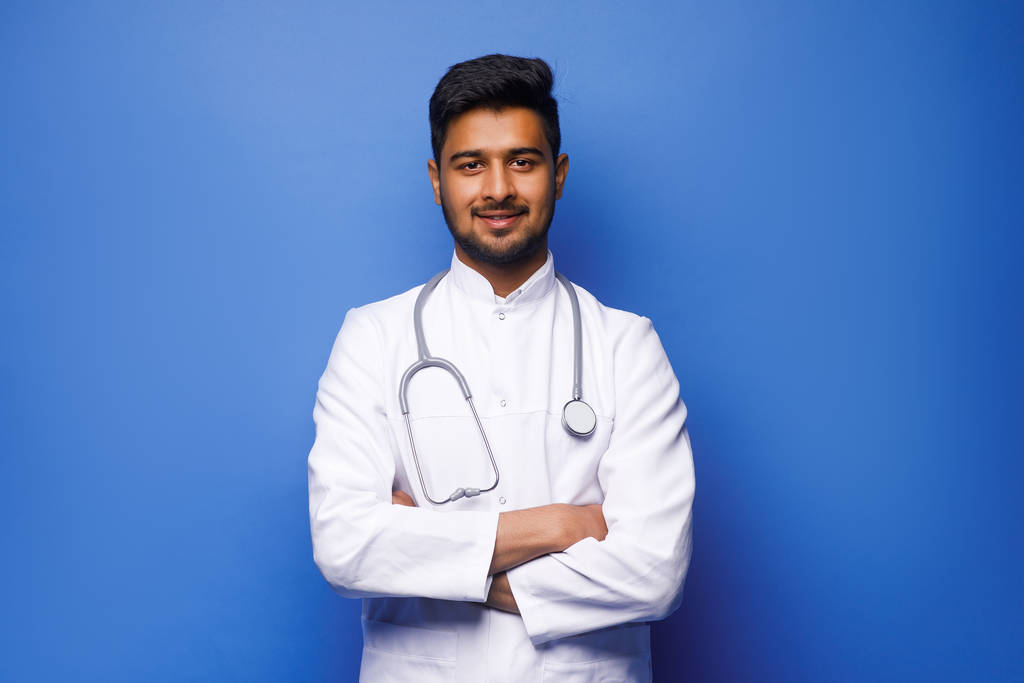 Intialainen mies lääkäri valkoisessa takissa sinisellä pohjalla
 - Valokuva, kuva