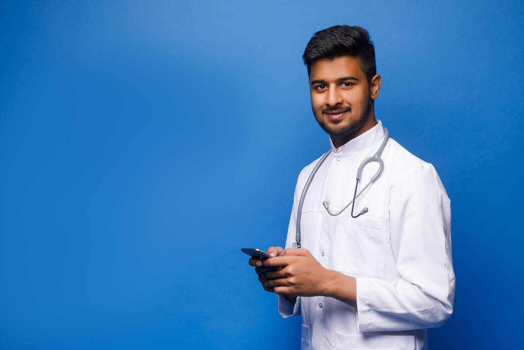 Ινδός άνδρας γιατρός σε λευκό παλτό σε μπλε φόντο - Φωτογραφία, εικόνα