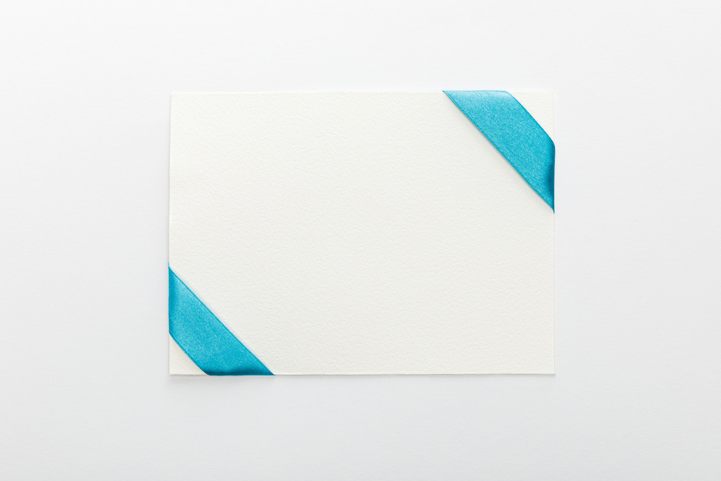Beyaz arkaplanda mavi saten kurdeleli boş kartın üst görünümü - Fotoğraf, Görsel