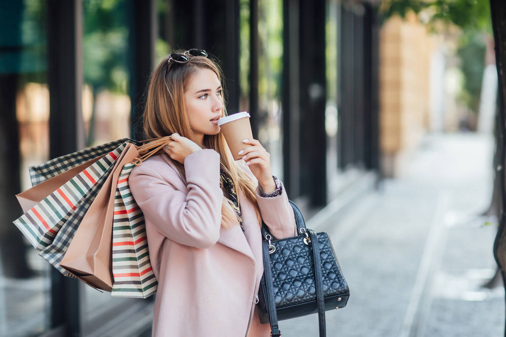 Όμορφη νεαρή ξανθιά γυναίκα με τσάντες ψώνια, επιλεκτική εστίαση - Φωτογραφία, εικόνα