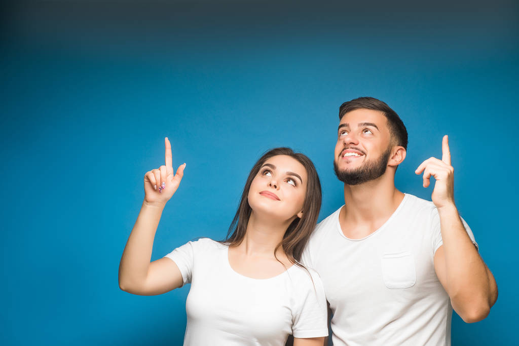 Portrait of happy young couple against blue background - Photo, Image