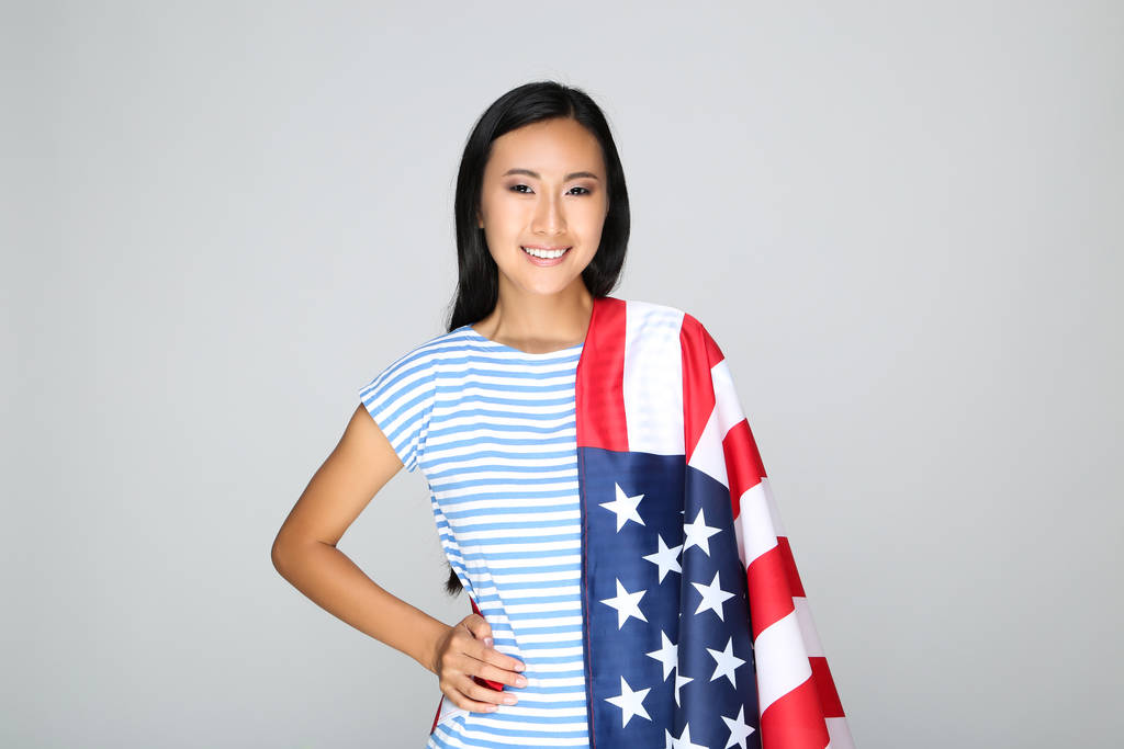 junge Frau mit amerikanischer Flagge auf grauem Hintergrund - Foto, Bild