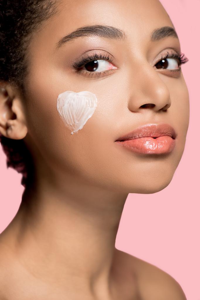 portrait of african american girl with heart of cream of cheek, isolated on pink   - Photo, Image