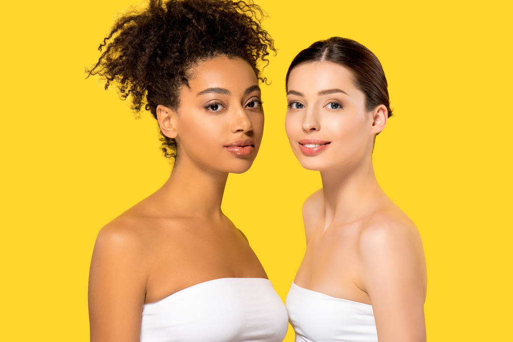 portret van mooie multi-etnische meisjes met een perfecte huid, geïsoleerd op geel - Foto, afbeelding