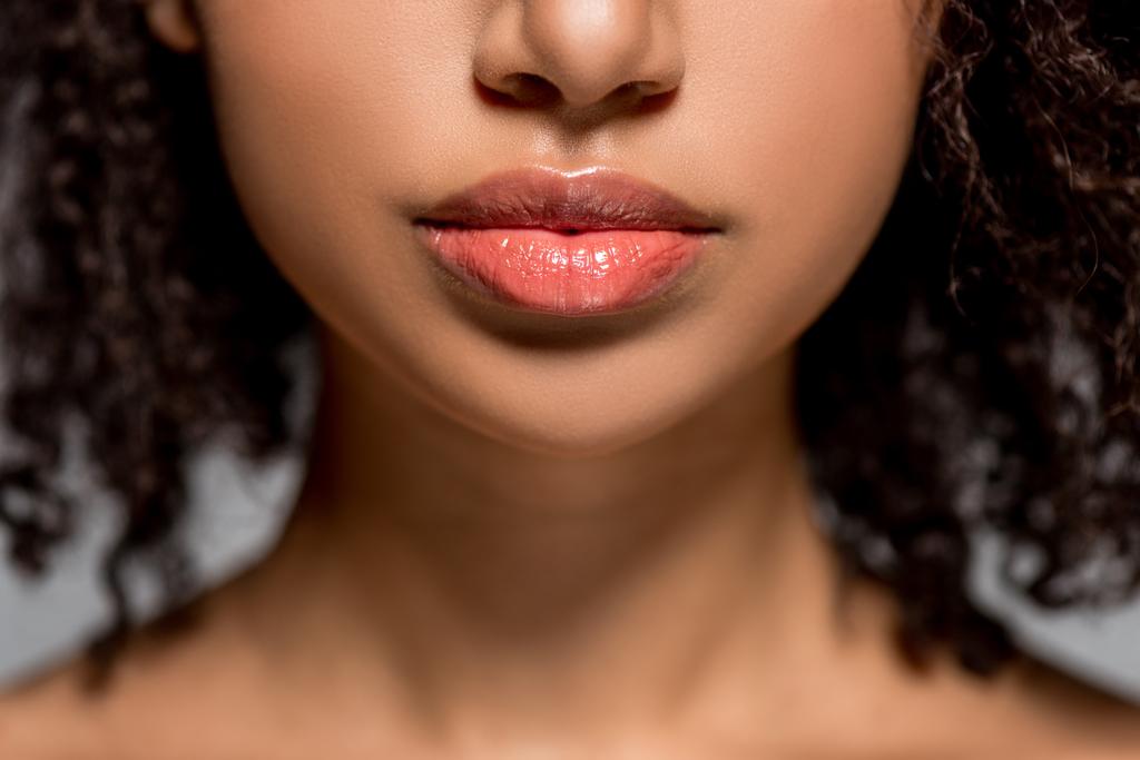 abgeschnittene Ansicht eines afrikanisch-amerikanischen Mädchens mit schönen Lippen, isoliert auf grau - Foto, Bild