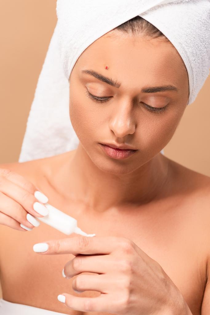 mujer atractiva y desnuda aplicando crema de tratamiento en la mano aislada en beige
  - Foto, imagen
