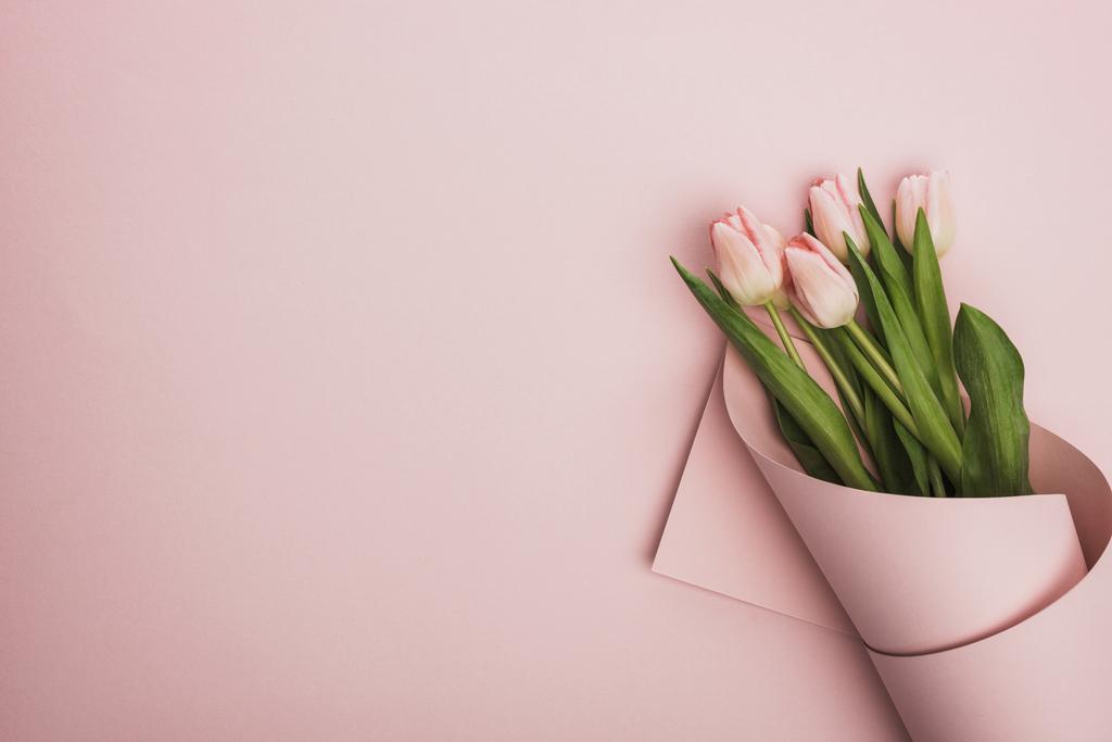 Draufsicht der Tulpen in Papier auf rosa Hintergrund gewickelt - Foto, Bild
