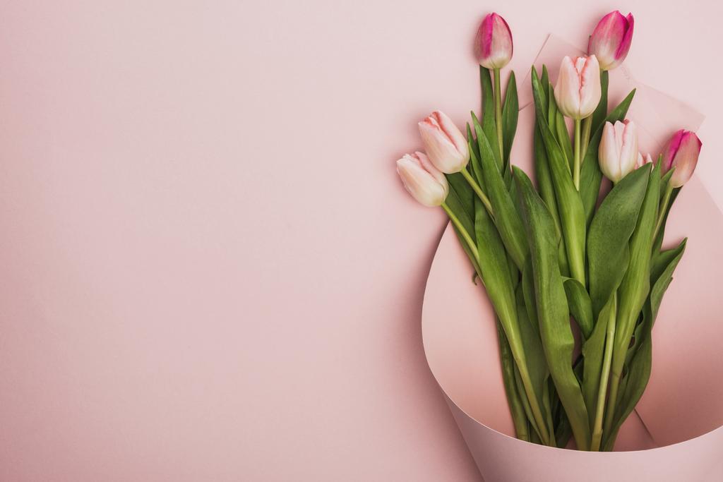 vista superior de tulipas rosa e roxo envolto em redemoinho de papel sobre fundo rosa
 - Foto, Imagem