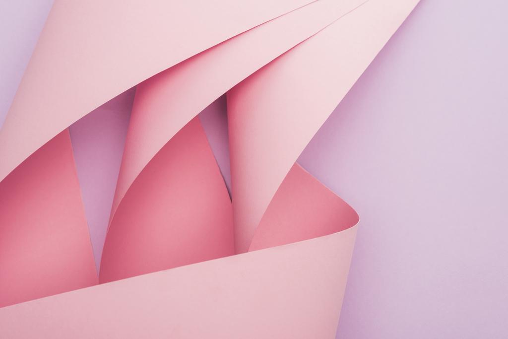 κορυφή άποψη του ροζ στροβιλίζεται χαρτί σε βιολετί φόντο - Φωτογραφία, εικόνα