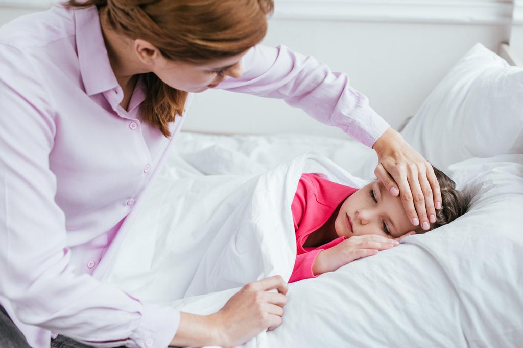 mère inquiète touchant le front d'une fille malade endormie avec fièvre
 - Photo, image
