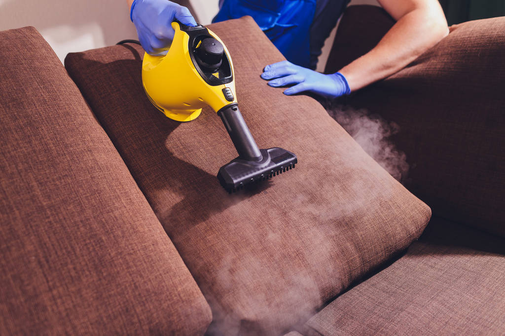 Сотрудник химчистки убирает грязь с мебели в квартире, крупным планом
. - Фото, изображение