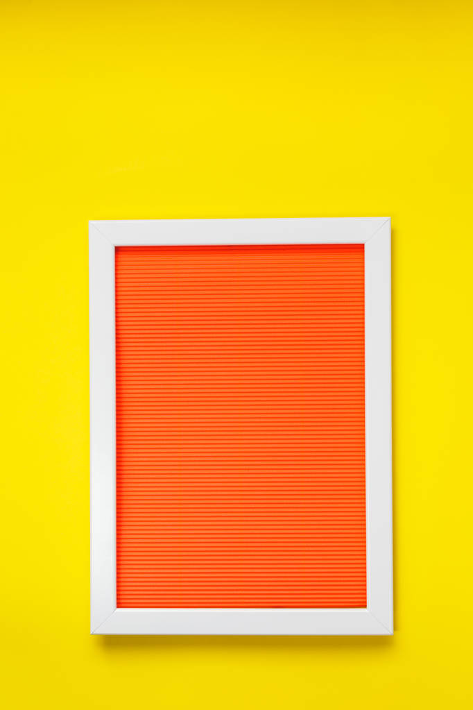 Cadre blanc vide sur une texture rouge orangé vif de papier froissé dans le volume de lignes horizontales suspendues au mur jaune. Concept de cadre. Pose plate. Espace vide
 - Photo, image