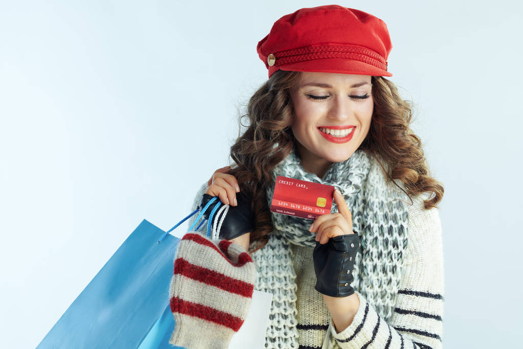 uśmiechnięta młoda kobieta shopper ze swetrami pokazującymi kartę kredytową - Zdjęcie, obraz