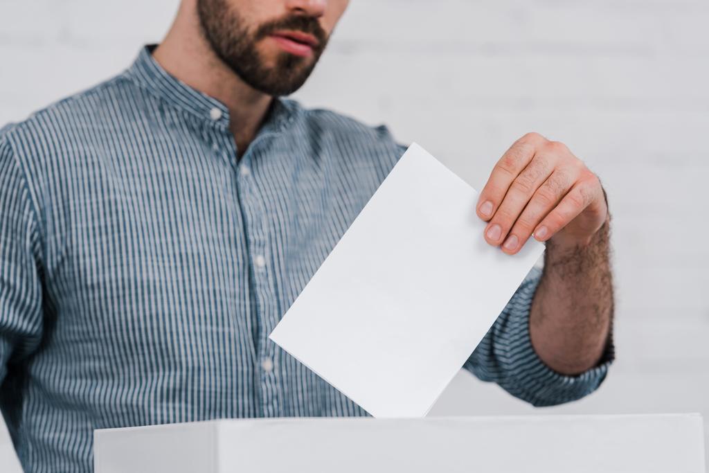 vista recortada del votante poniendo boleta en blanco en la caja de votación
  - Foto, Imagen