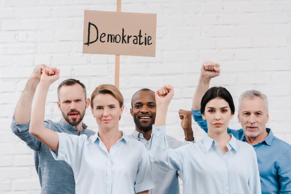 group of multicultural people gesturing near placard with demokratie lettering - Photo, Image