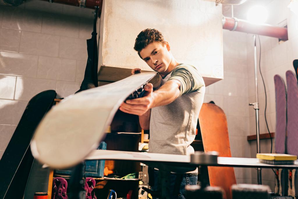 selective focus of worker holding snowboard in repair shop  - Photo, Image