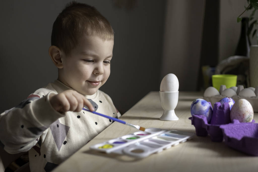 Pikkulapsi poika maalaus pääsiäismunia valmistautuu loma. Pääsiäisperinne
  - Valokuva, kuva